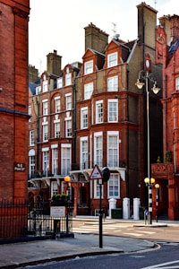 Victorian-style red brick buildings with ornate details stand along a quiet street corner. The architecture features multiple stories, white window frames, and decorative wrought iron balconies. Street lamps and traffic signs are visible in the foreground, along with a sign for Cadogan Square SW1.