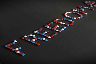 Red, blue, and white candies are arranged on a dark surface to spell the word 'FREEDOM'.