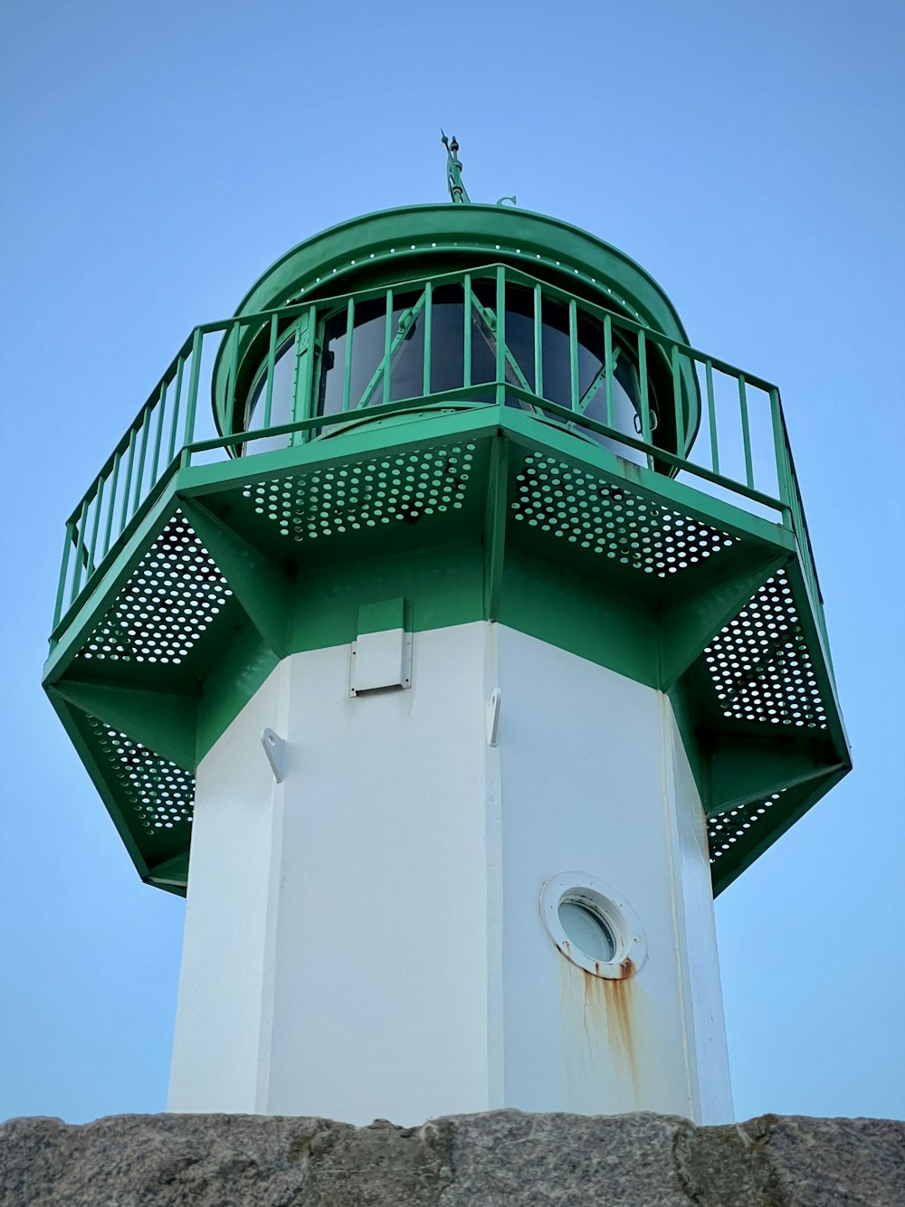 a green and white light house on top of a hill