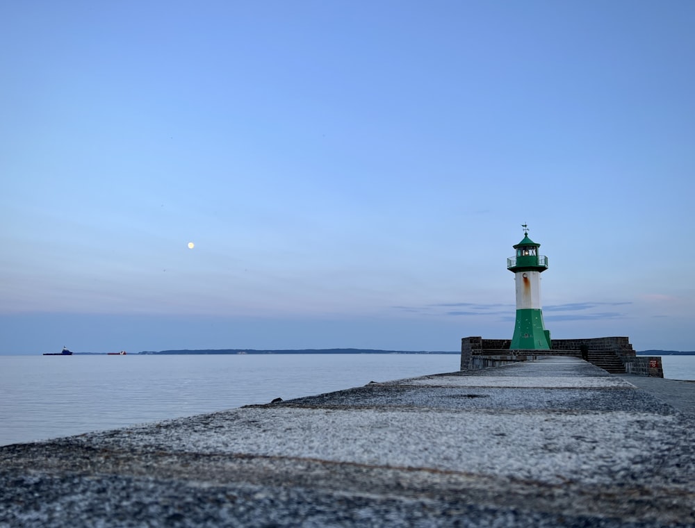 a green and white light house sitting on top of a pier