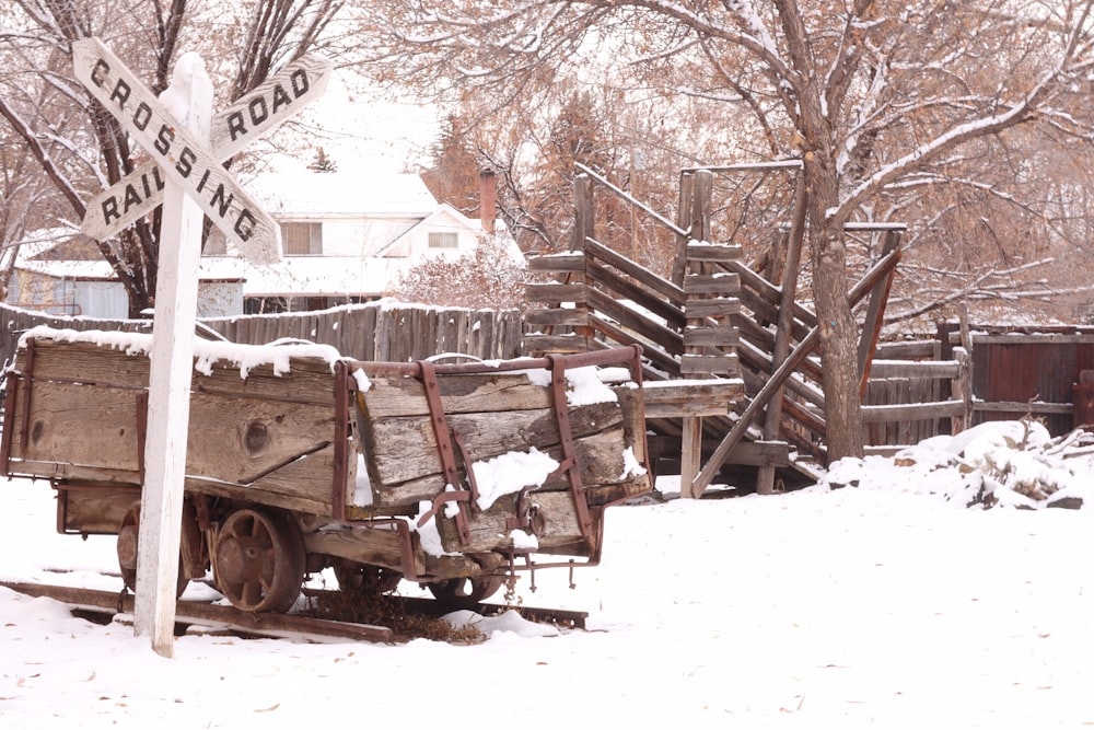 an old wooden wagon sitting in the snow next to a street sign