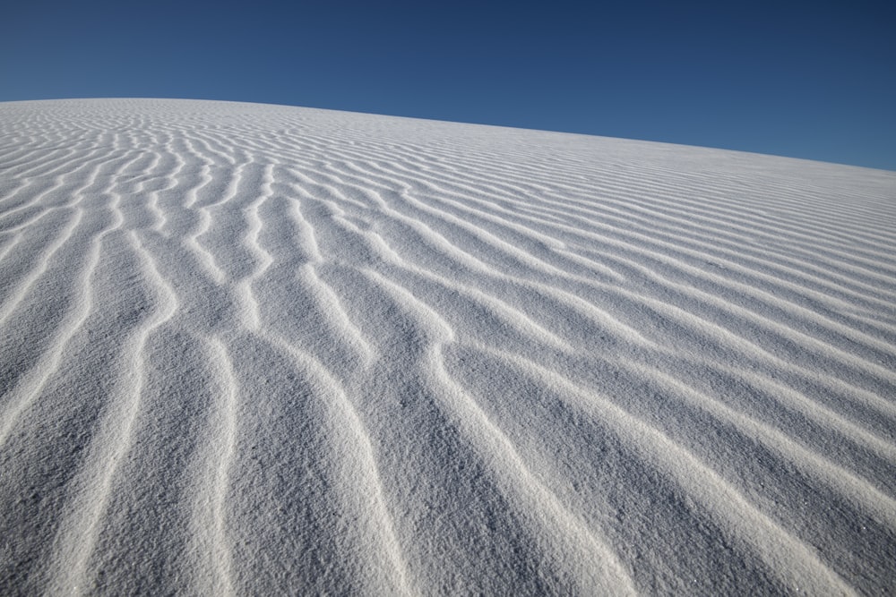 a large expanse of white sand with a blue sky in the background