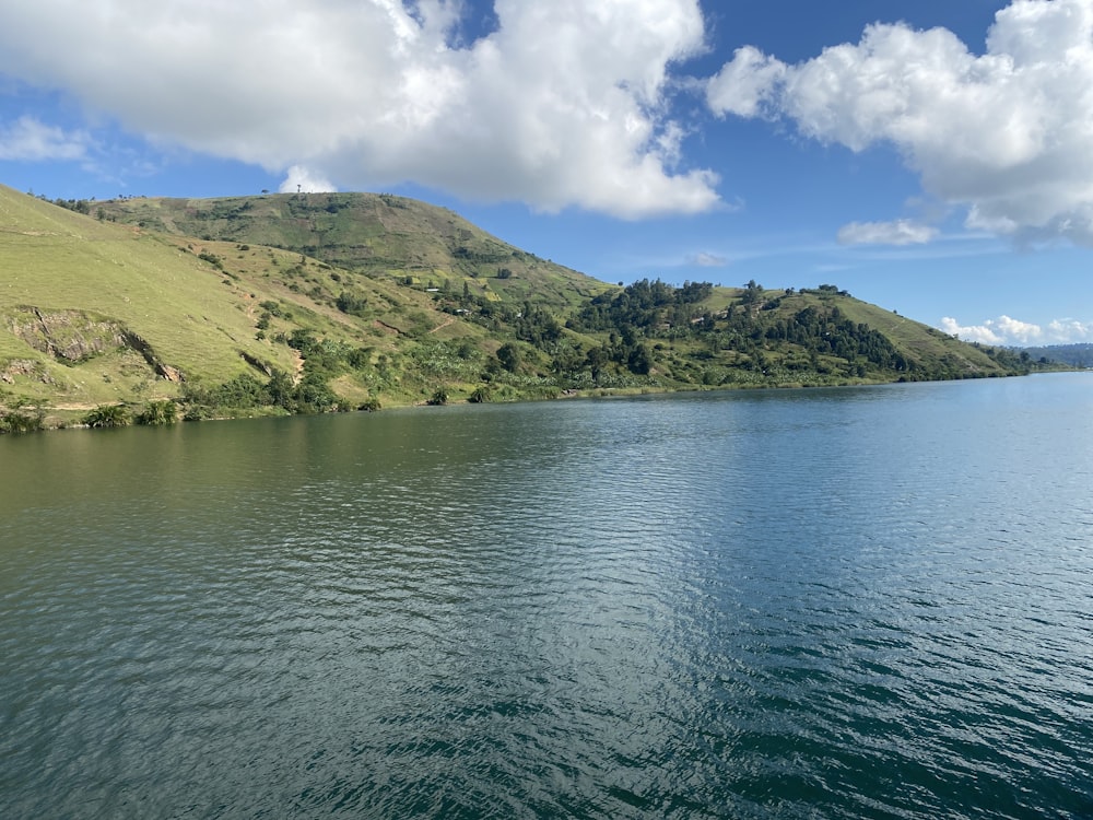 a large body of water surrounded by a lush green hillside