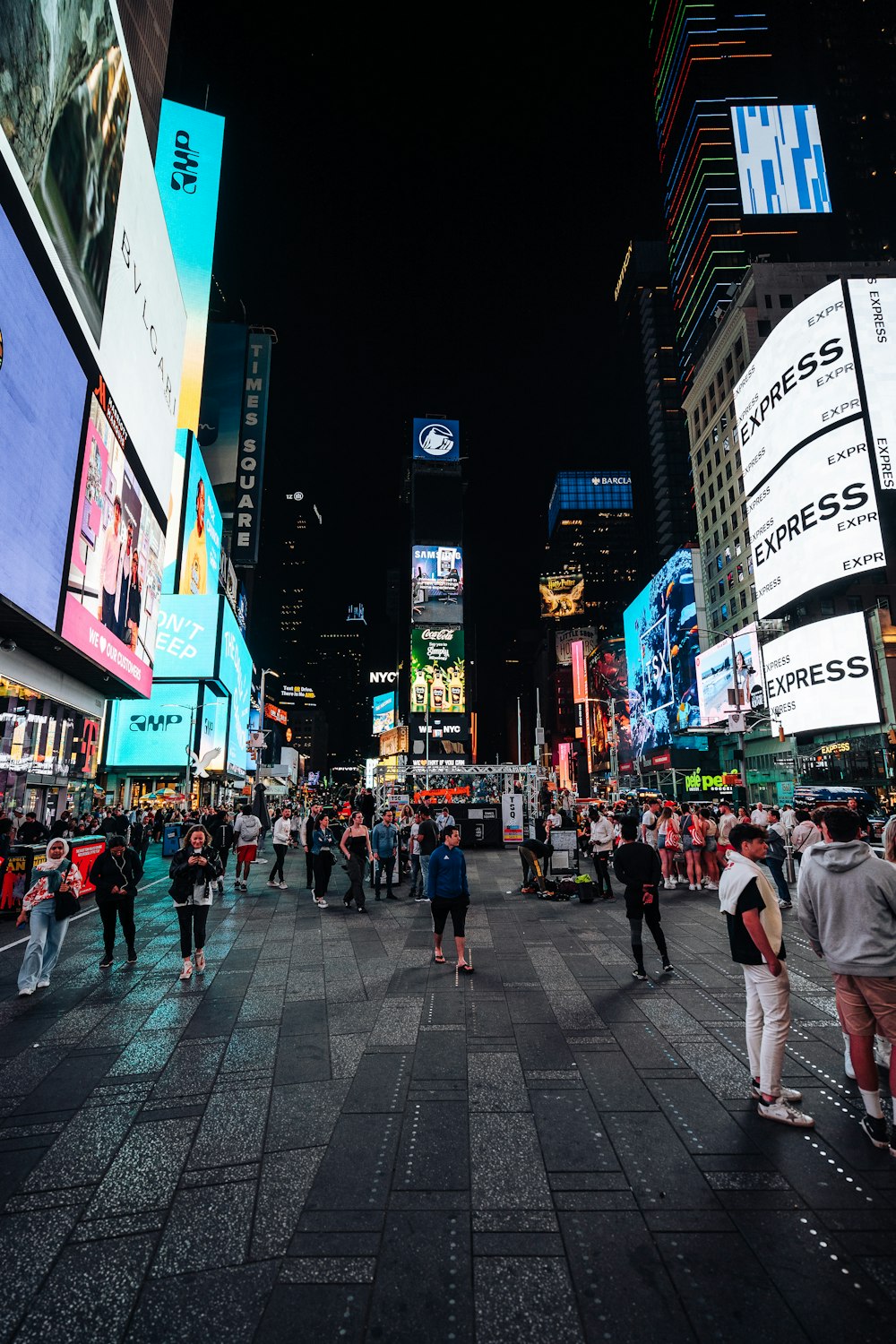 a crowd of people walking around a city at night