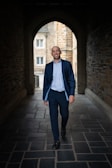 a man in a suit walks through a tunnel