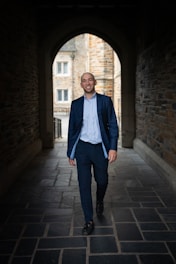 a man in a suit walks through a tunnel