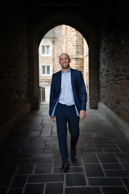 a man in a suit walks through a tunnel