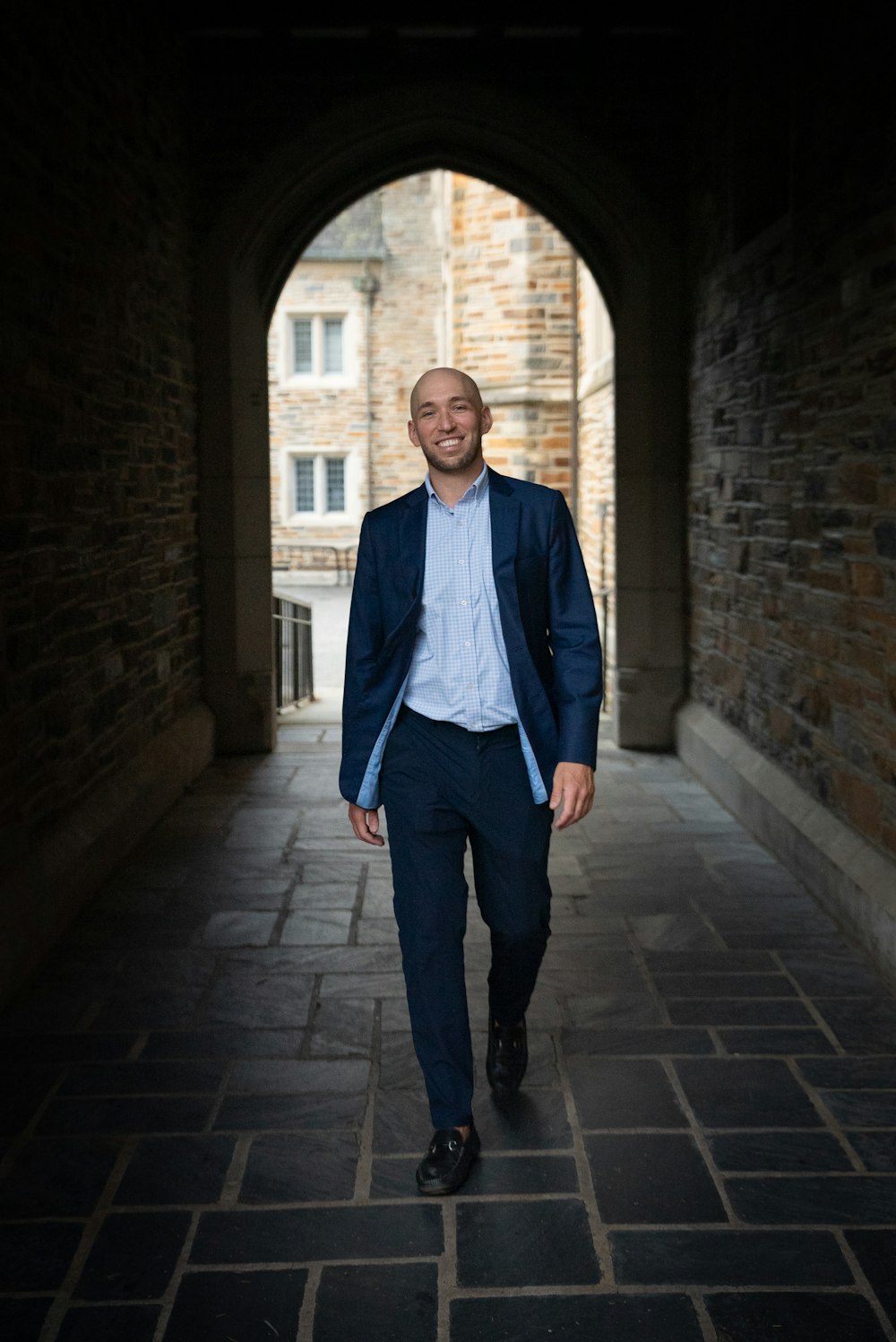 a man in a suit walks through a tunnel