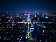 Nighttime cityscape with glowing signs and bustling streets alive with energy.