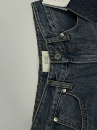 A pair of classic dark denim jeans laid out flat with a leather belt.