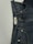 A pair of dark blue denim jeans featuring a visible button and belt loops. There is a tag on the inside waistband with text. The material has a textured appearance characteristic of denim fabric.