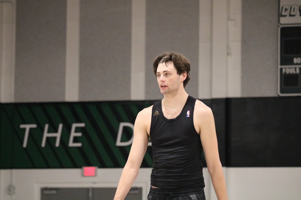 a man standing in a gym holding a tennis racquet