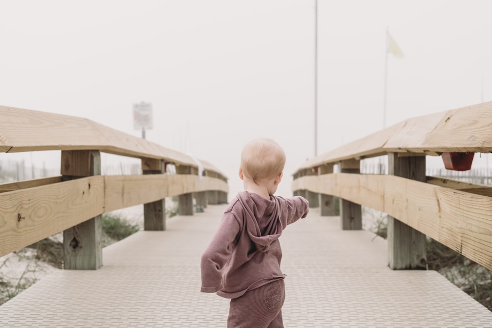 a small child walking across a wooden bridge