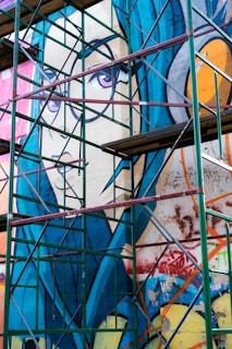 Wide shot of the mural in progress, with scaffolding and community members watching.