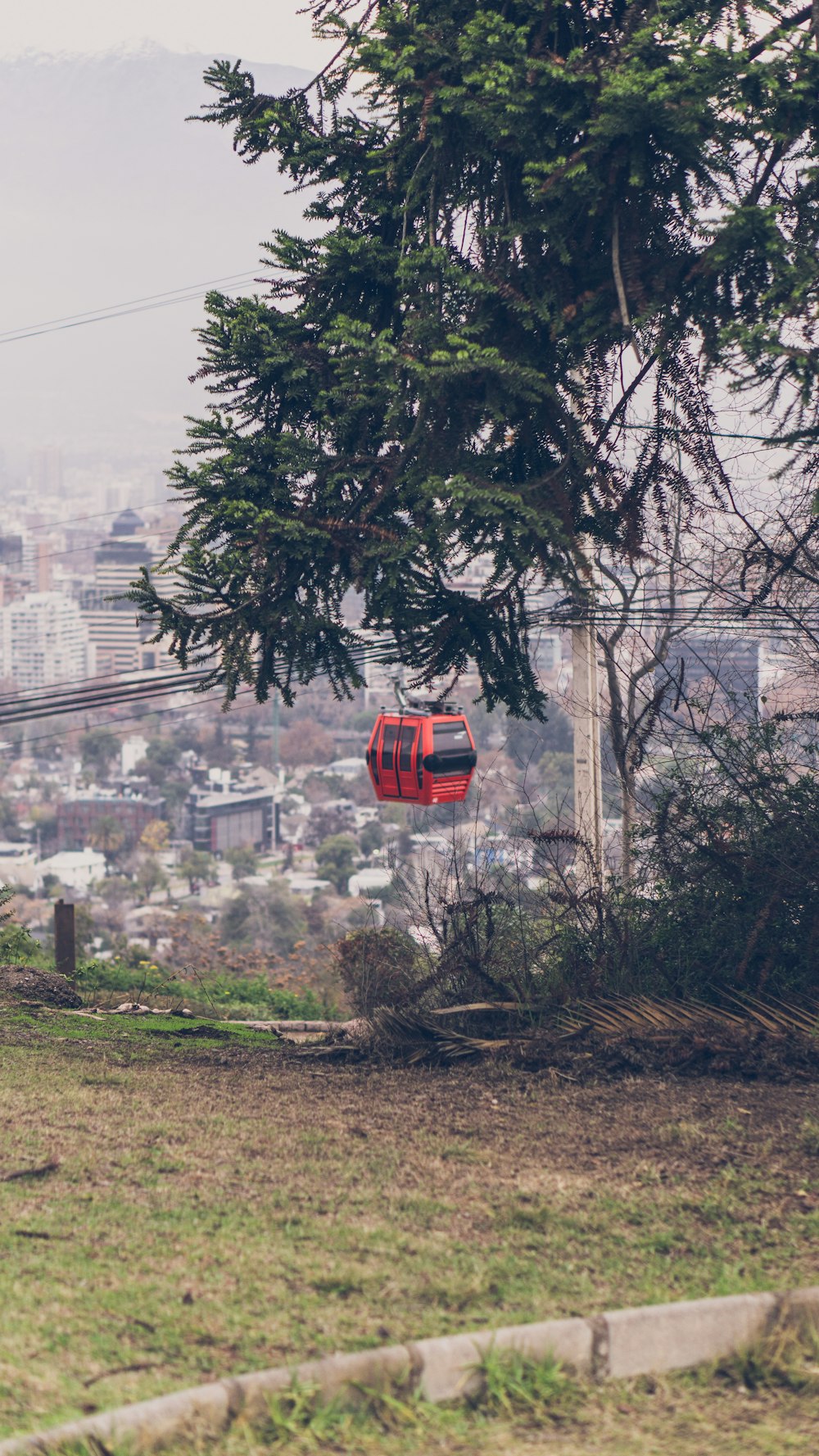 a red cable car going down a hill with a city in the background