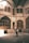An individual stands in the center of a historical courtyard, capturing a photograph with a smartphone. The architecture features arched windows and intricate details, and the interior is illuminated by soft natural light filtering in from above.