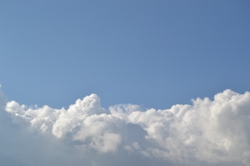 A clear sky with fluffy, white clouds at the bottom part of the image. The clouds appear soft and billowy against a blue backdrop.