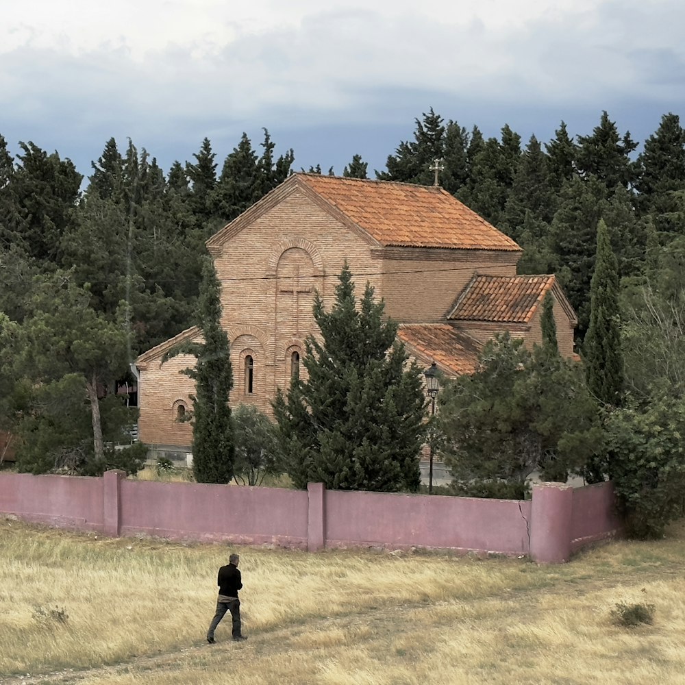 Una persona caminando en un campo con una iglesia en el fondo