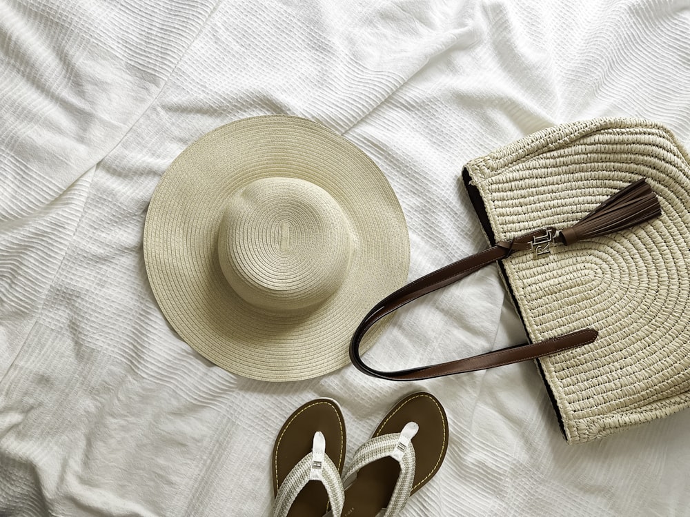 a pair of sandals and a hat on a bed