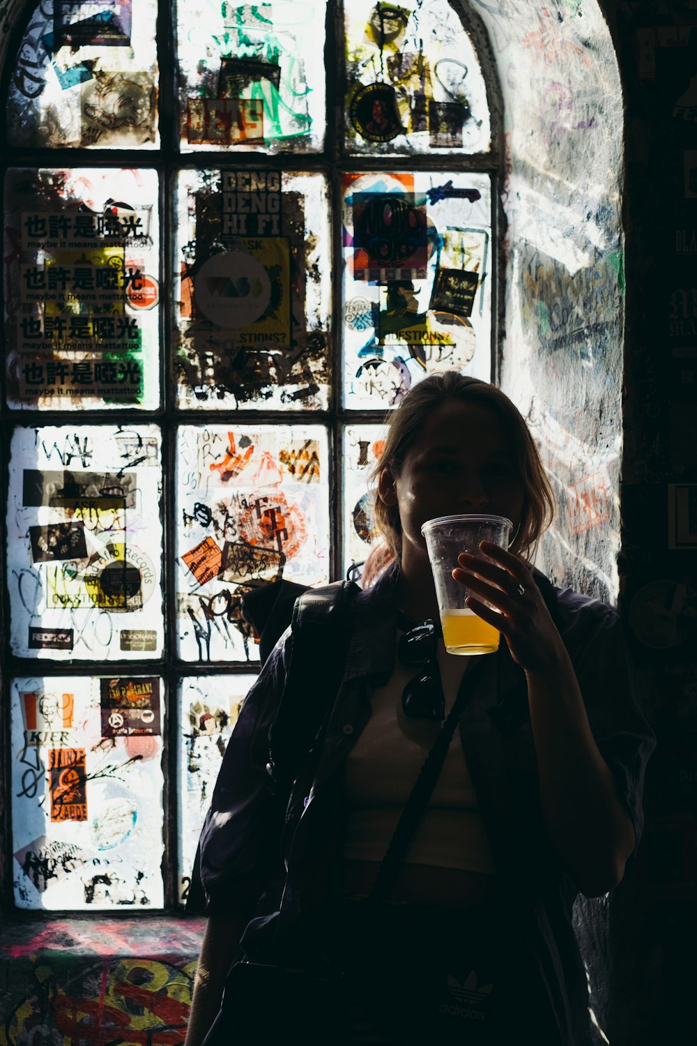 a woman standing in front of a window holding a glass