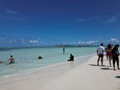 Happy travelers enjoying a sunny beach destination with clear blue water.