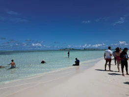 Happy travelers enjoying a sunny beach destination with clear blue water.