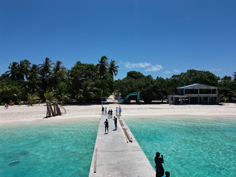 a group of people standing on a pier next to a body of water