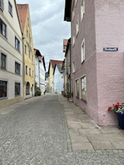 A charming cobblestone street in Suchitoto lined with colonial buildings and colorful flowers.
