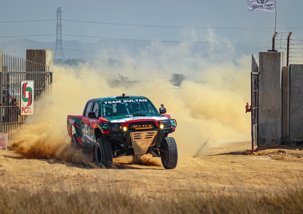 a truck driving down a dirt road near a fence