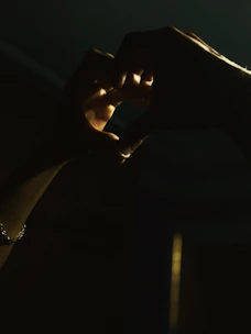 Hands gently holding a radiant heart symbol glowing with light.