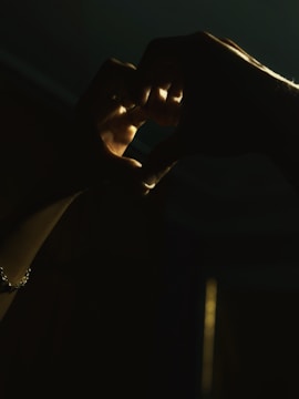 Hands gently holding a heart-shaped symbol of donation in warm light.