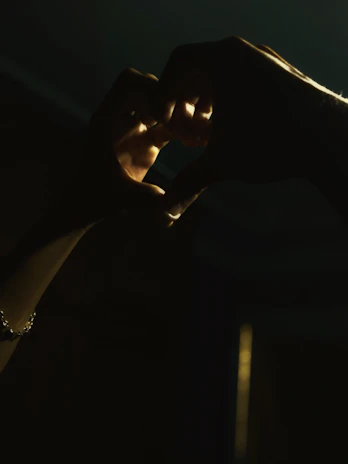 Hands forming a heart shape over a softly glowing Reiki symbol.