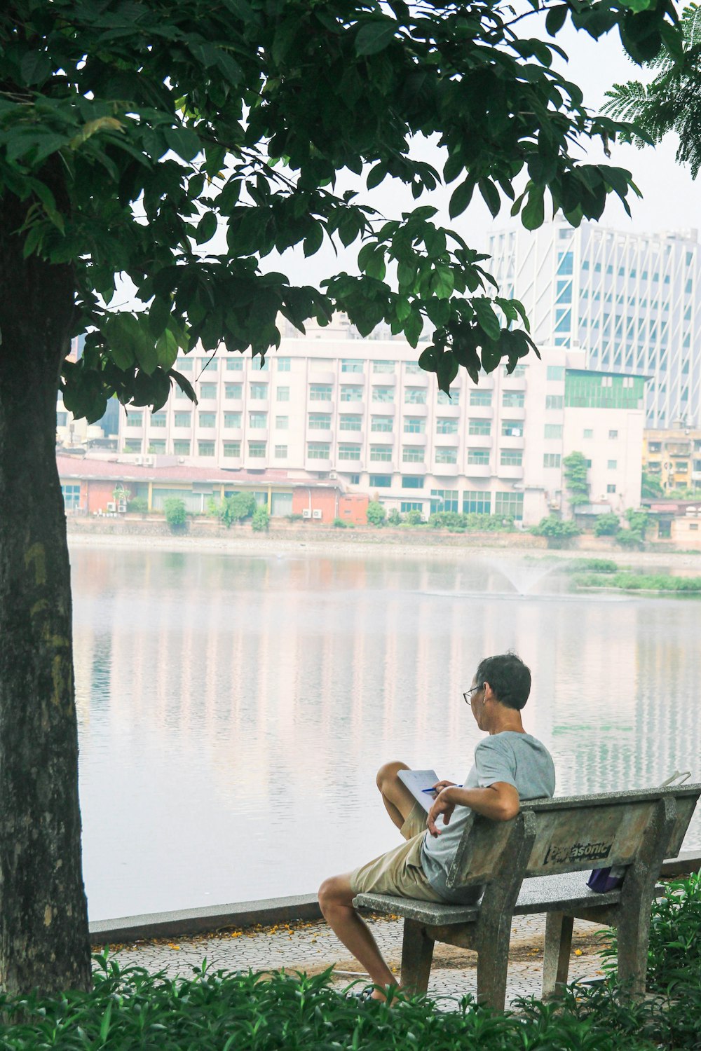 a man sitting on a bench next to a lake