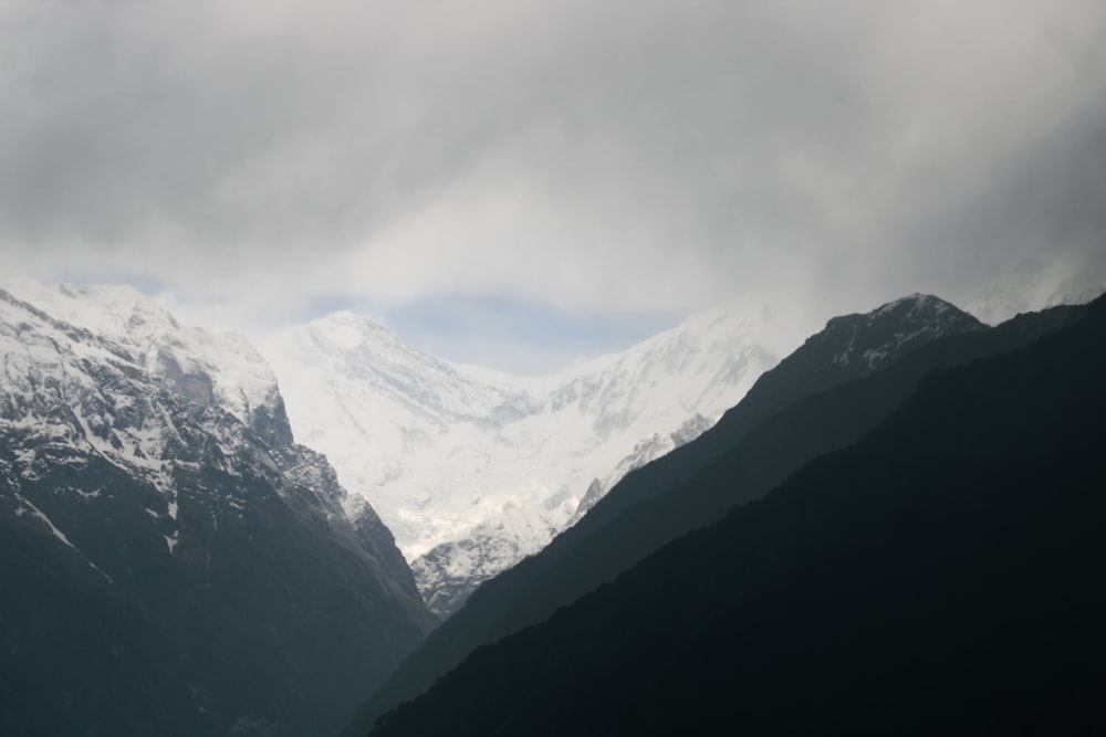 the mountains are covered in snow and clouds