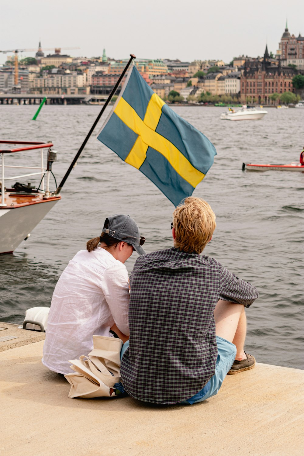 two people sitting on a dock with a flag
