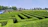 Photo of a large modular maze set up on a sunny farm landscape with families enjoying the pathways.