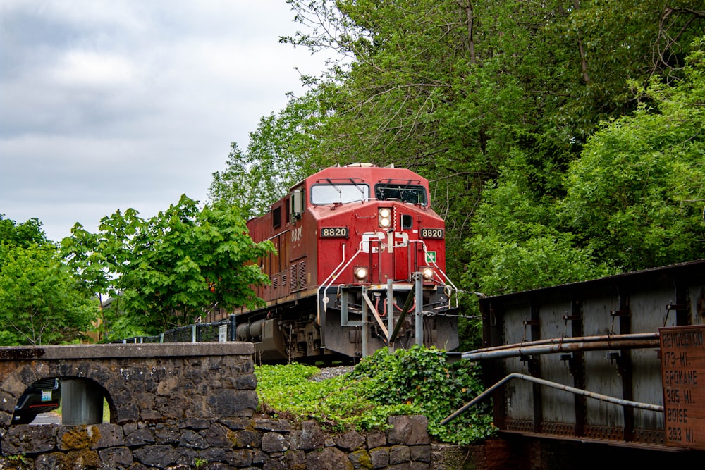 a red train traveling through a lush green forest