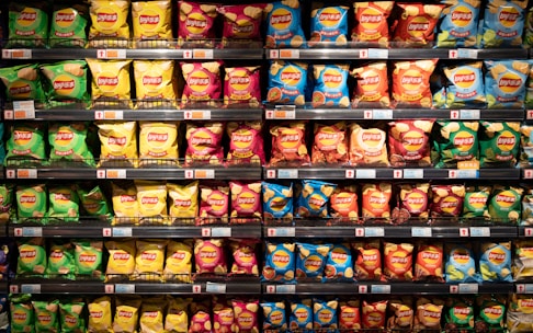 A well-organized store shelf displays various flavors of Lay's chips. The bags exhibit bright colors, with each row containing different varieties such as green, yellow, pink, blue, and red packaging.
