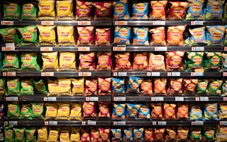 A well-organized store shelf displays various flavors of Lay's chips. The bags exhibit bright colors, with each row containing different varieties such as green, yellow, pink, blue, and red packaging.