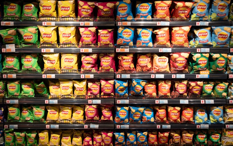 Prateleira de supermercado lotada de pacotes de snacks e chips coloridos