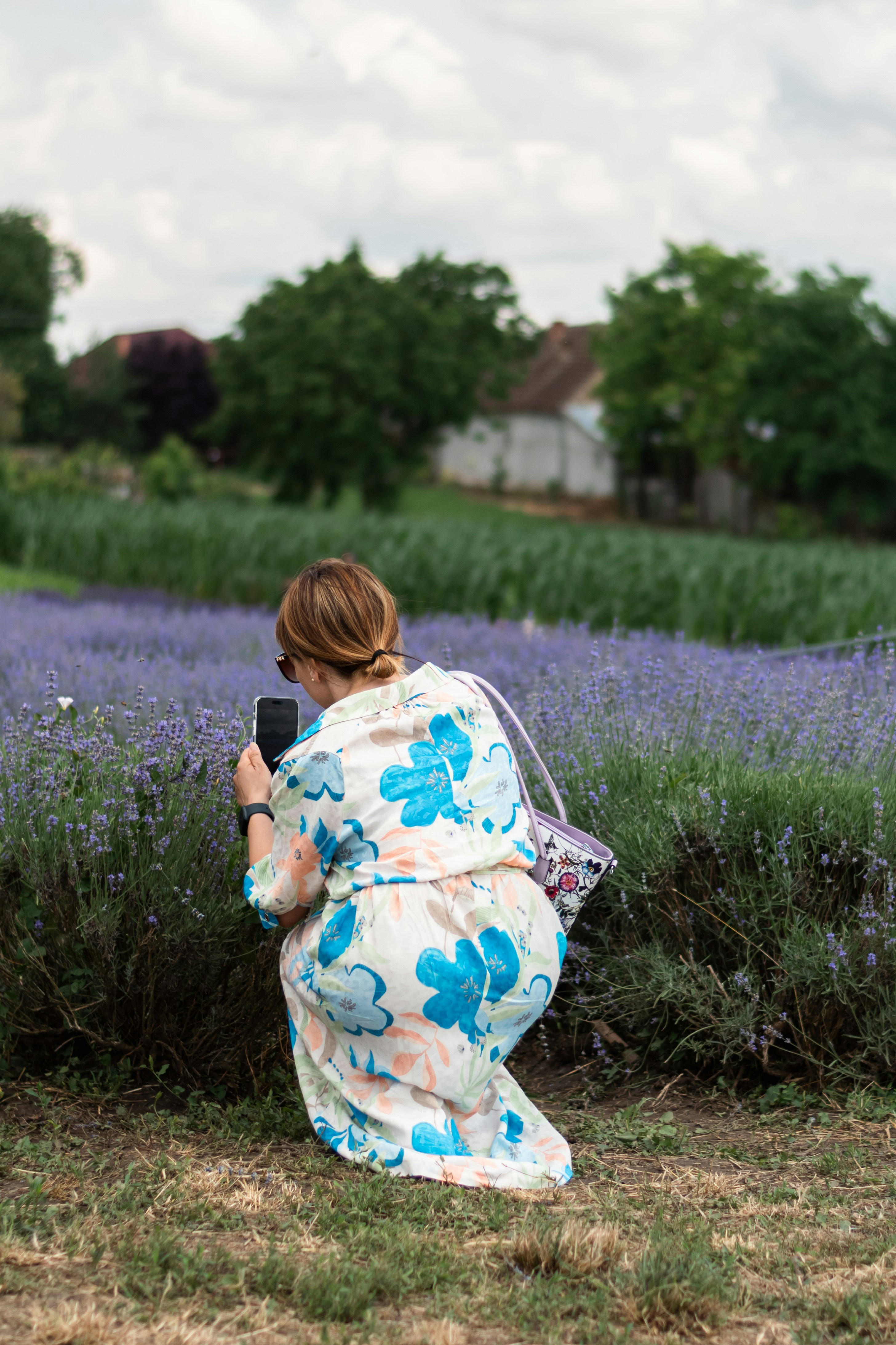 a woman in a floral robe taking a picture of a lavender field