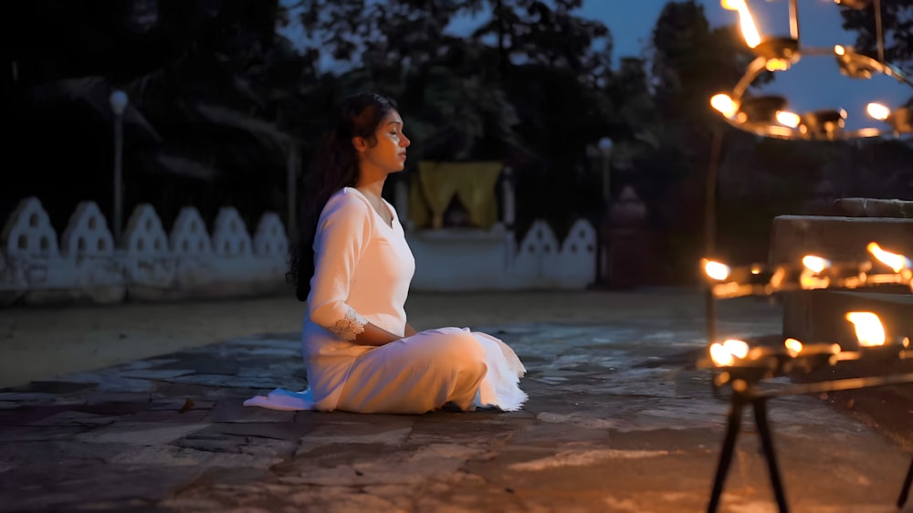 a woman sitting on the ground in front of a light