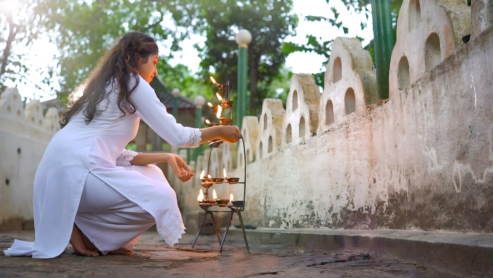 a woman in a white dress lighting candles