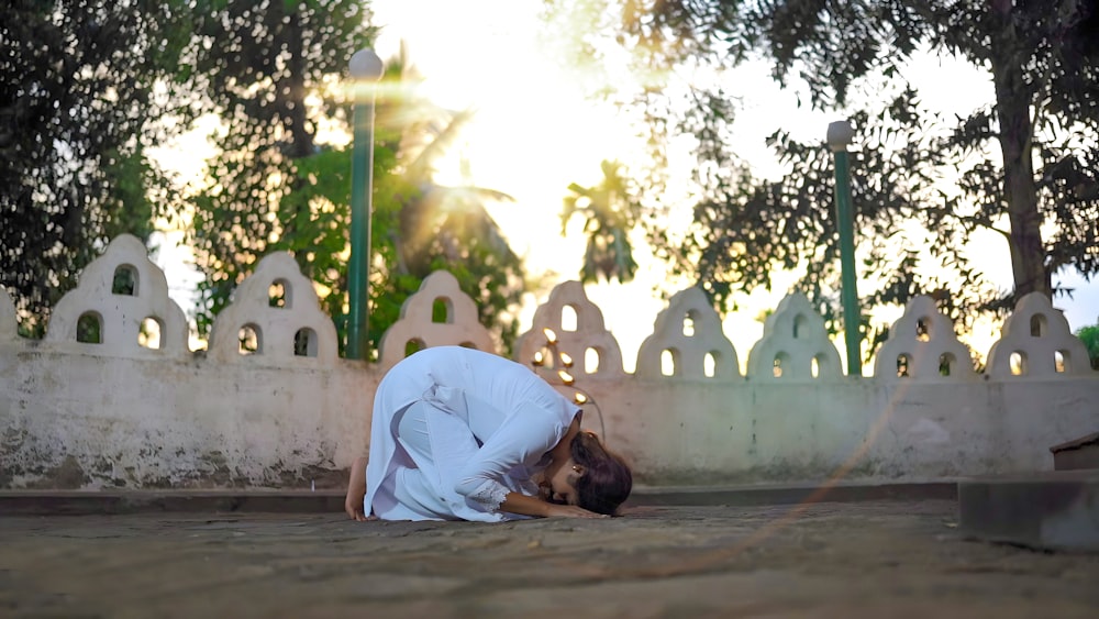 a woman kneeling down on the ground with her head in her hands
