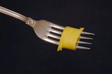 Close-up of perfectly portioned spaghetti twirled on a fork with a creamy sauce, set against a minimalist cream and pasta yellow background.