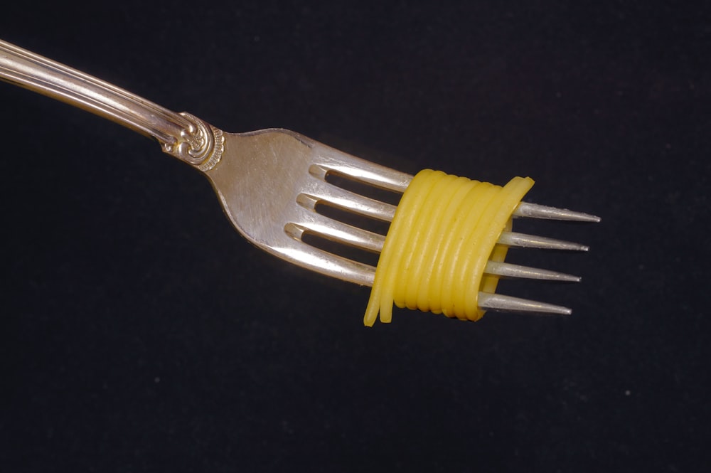 a close up of a fork with yellow noodles on it