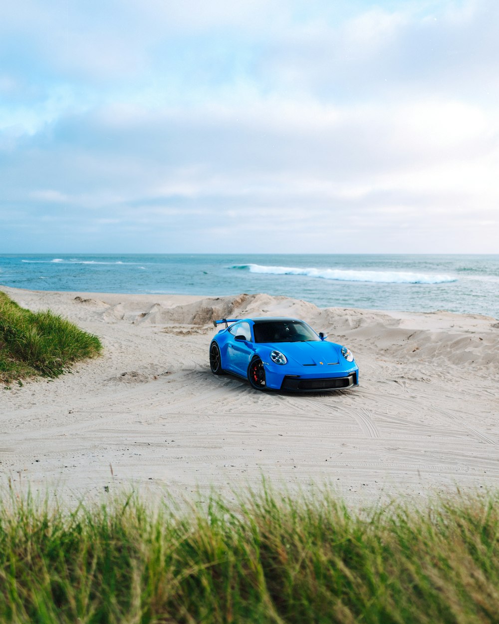 Un'auto sportiva blu parcheggiata su una spiaggia sabbiosa