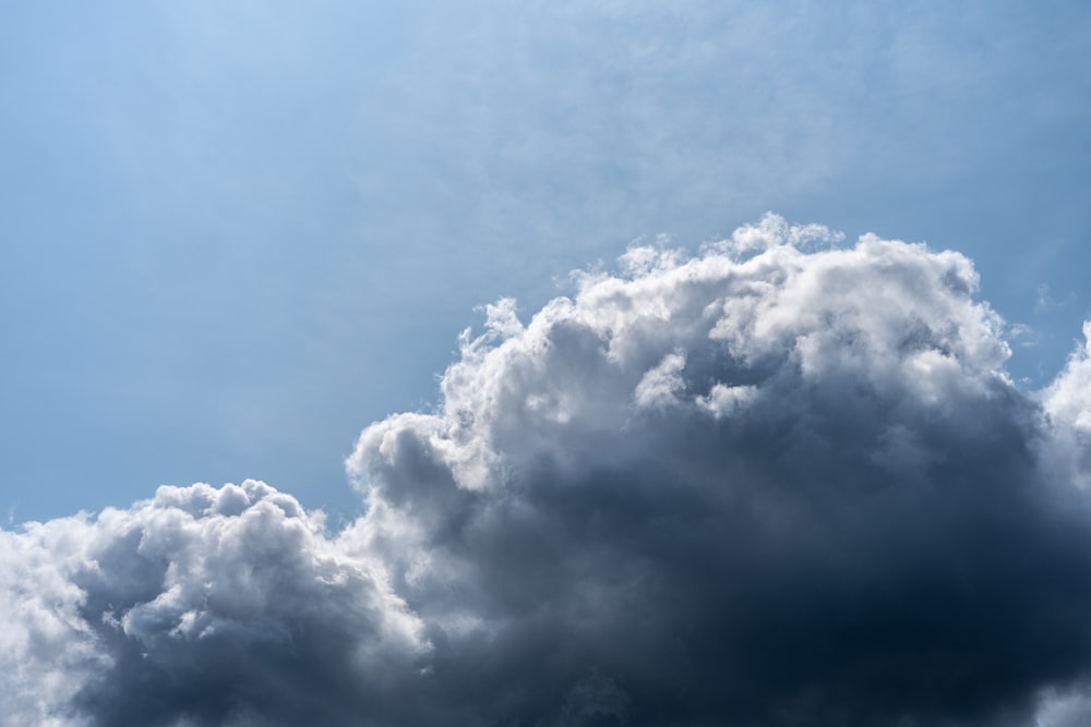 a plane flying through a cloudy blue sky