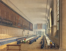 A grand dining hall with long tables covered in white tablecloths extends into the distance. Rows of people dressed similarly are seated along both sides of the tables. High ceilings and large windows allow natural light to flood the room. Large wall paintings and wooden paneling add to the ornate and formal atmosphere.