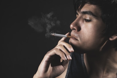 a man smoking a cigarette in the dark